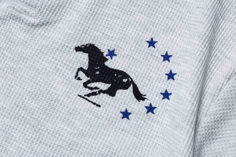 Close-up of a light gray knit polo tee with black embroidered Mustang graphic and blue stars on the chest