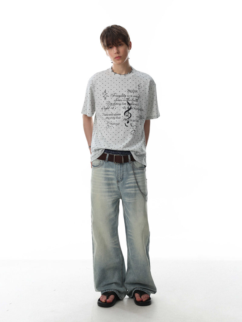 Relaxed gray graphic tee with micro-print script, worn with baggy faded jeans and sandals on a white background