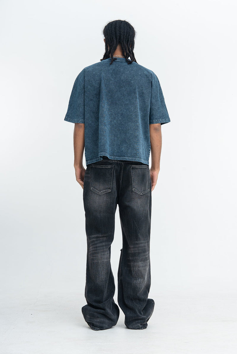 Vintage washed oversized blue graphic tee worn with dark baggy jeans, shown from the back on a model