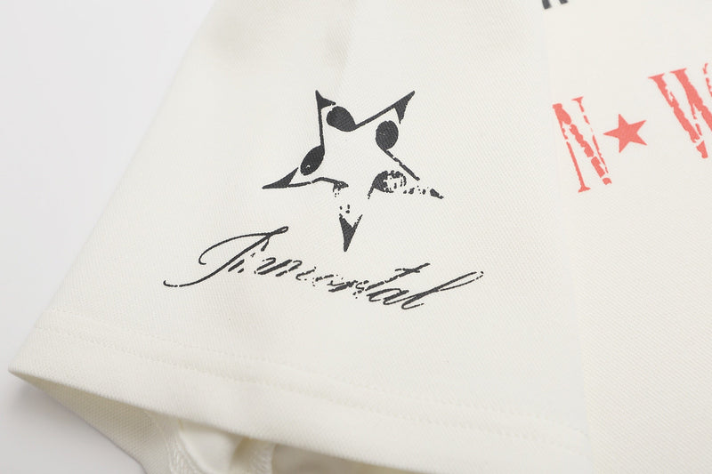Close-up of a white graphic polo shirt with black star print and red distressed lettering, Y2K streetwear style