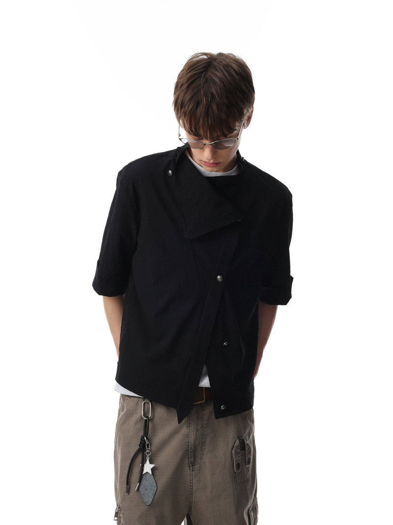 Model wearing a black asymmetrical stand-collar cotton shirt with short sleeves and layered minimal streetwear styling