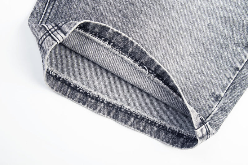 Close-up of cuffed hem on gray denim jeans with visible seam and fade