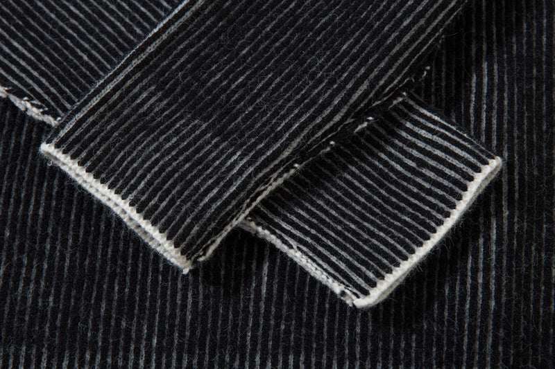Close-up of folded ribbed sleeve cuff on black striped knit sweater