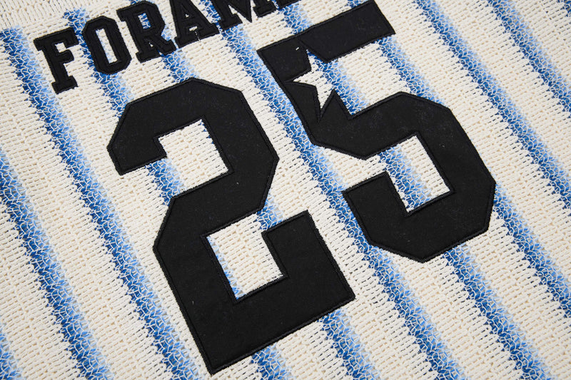 Close-up of a cream knit varsity tee with blue stripes and black embroidered FORAY 25 lettering