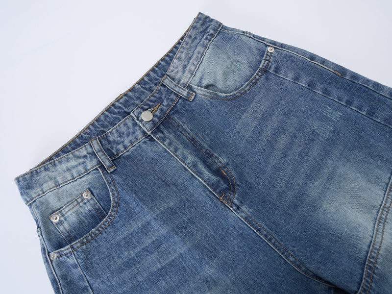 Close-up of front waistband and pocket on blue denim jeans with panel seams and rivets