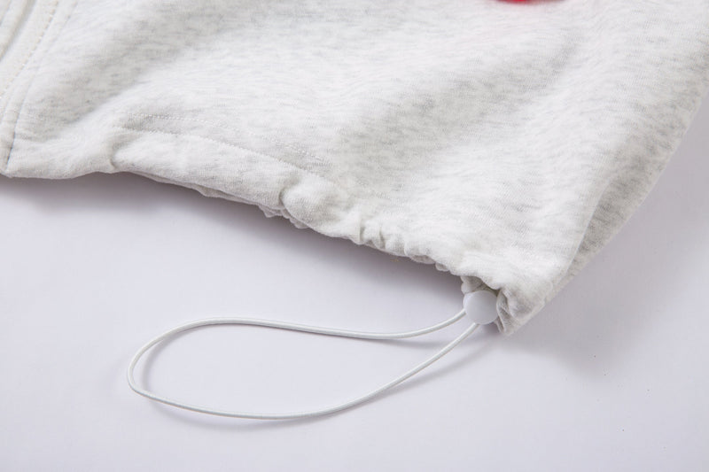 Close-up of the bottom hem and drawstring on a light gray hooded jacket