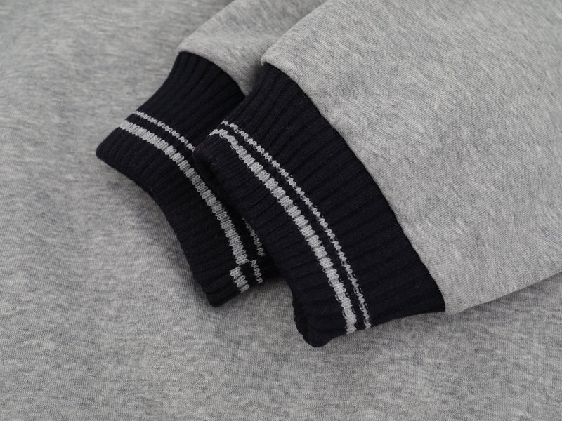 Close-up of navy ribbed cuff with gray striped trim on gray sweatshirt sleeve