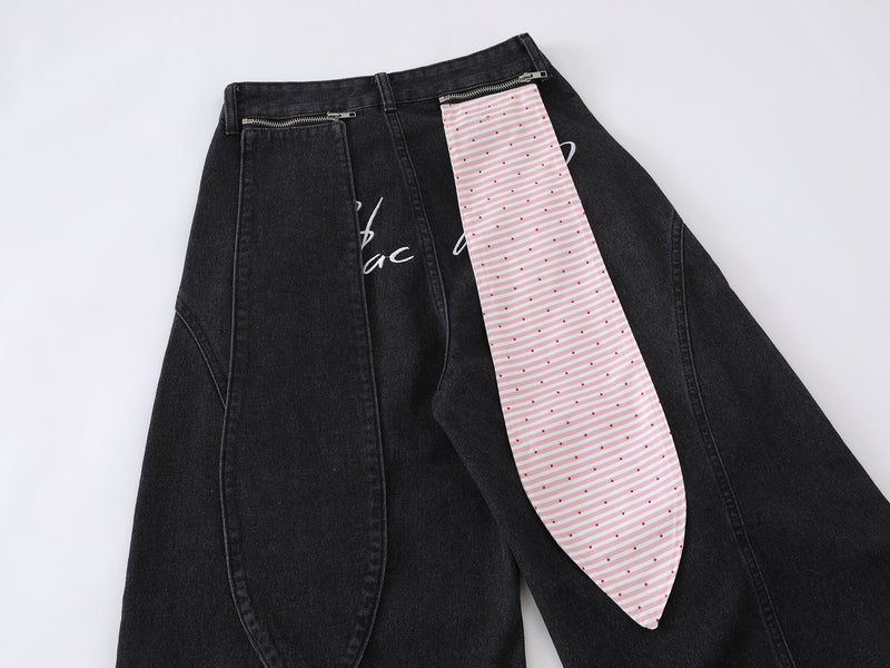 Close-up of black jeans with pink striped panel and top zipper pockets