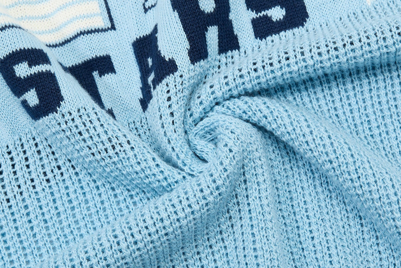 Light blue knit polo with navy varsity lettering and textured collegiate streetwear fabric close-up