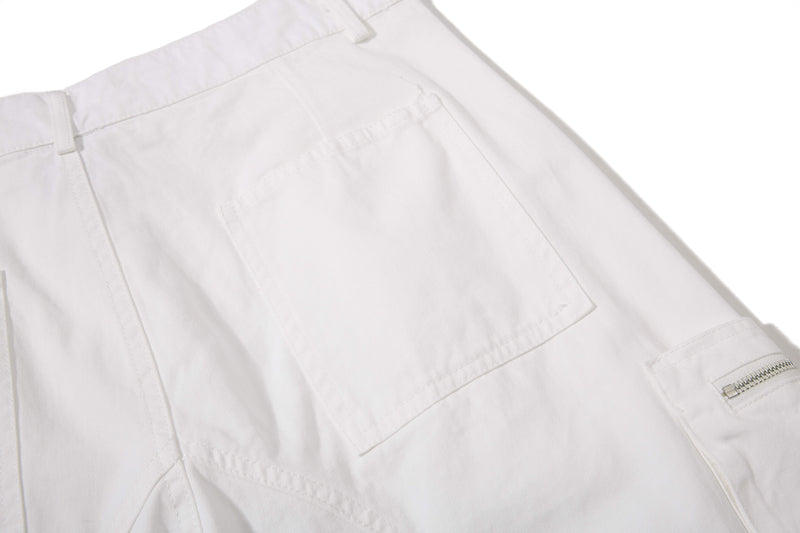 White shorts back pocket flap and side zipper detail, close-up