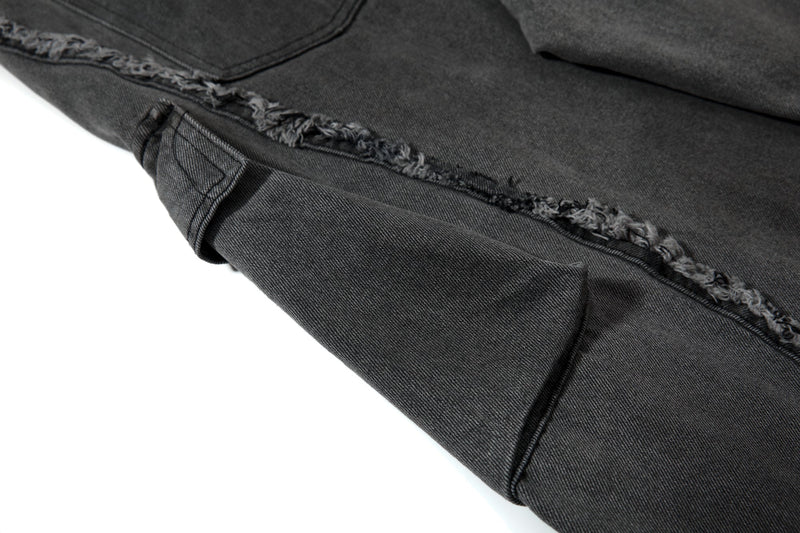 Close-up of lower leg side panel and frayed seam on black denim pants