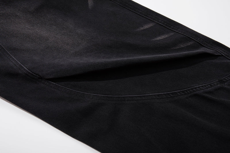 Close-up of dark denim fabric showing a curved seam and washed fading