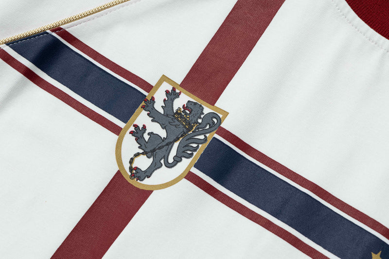Close-up of a retro football jersey tee with burgundy and navy stripes and a vintage crest on white fabric