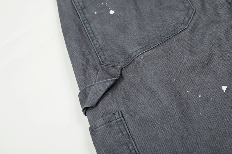 Close-up of gray jeans side utility pocket with paint splatters and visible stitching