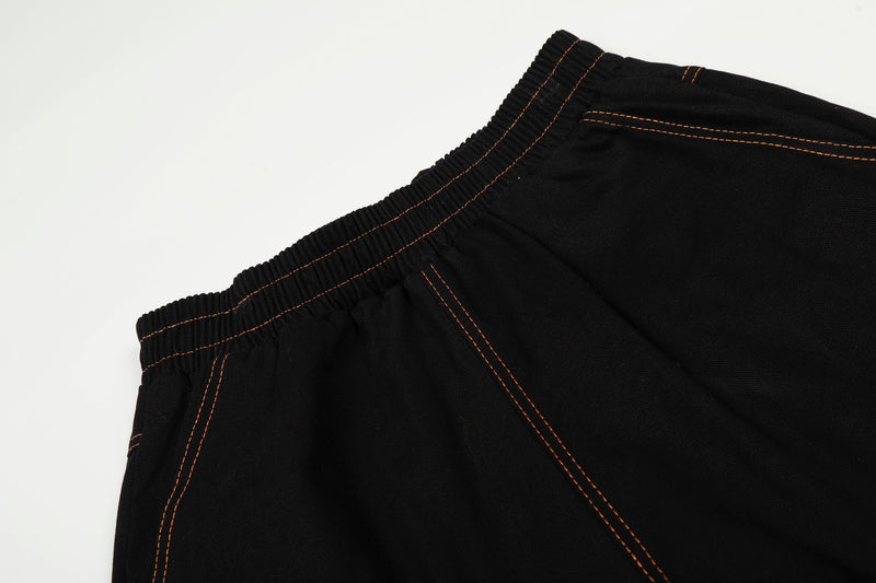 Close-up of black elastic waistband with orange contrast stitching on wide-leg pants