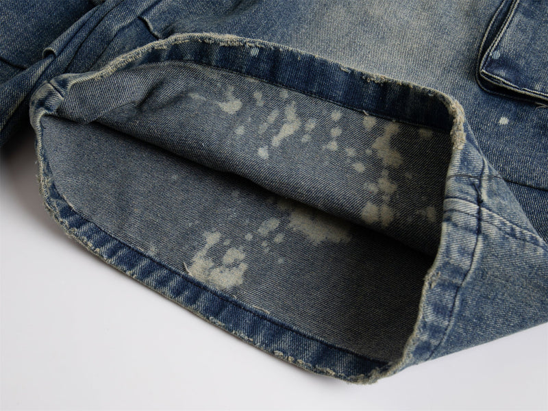 Close-up of rolled cuff and interior denim hem on distressed blue shorts