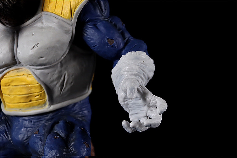 Close-up of the Seakoff Great Ape Vegeta Collectible Figure from Dragon Ball Z, showcasing a muscular character with detailed, textured skin. The character dons blue and white attire with yellow and gray chest armor, as it extends a hand against a black background. Measures 36cm.