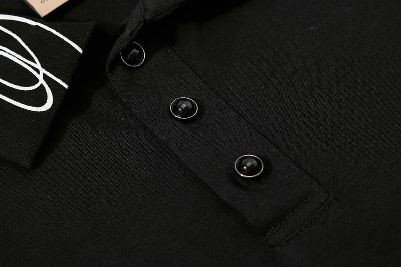 Black cotton polo tee with glossy snap buttons and white graphic sleeve detail, styled for modern streetwear looks