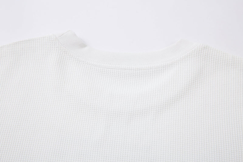 Close-up of white waffle-knit crewneck collar and shoulder seam