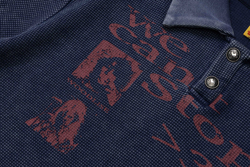Close-up of a navy vintage washed polo tee with faded red graphic print and textured knit fabric, retro streetwear style