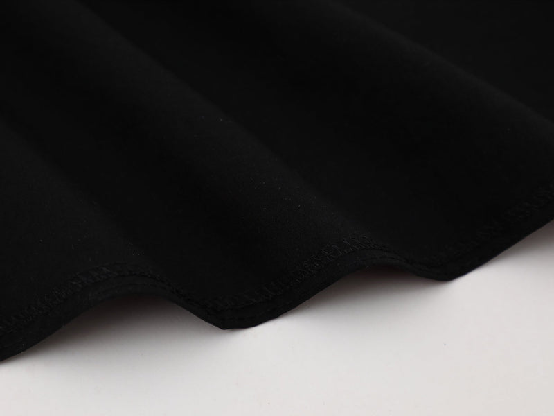 Close-up of a black streetwear button-up shirt hem with subtle stitched detailing on a clean white background