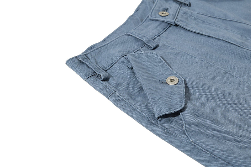 Close-up of blue cargo pant side pocket and buttoned flap detail