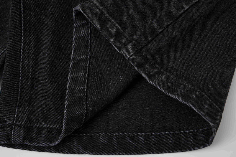 Close-up of black denim shorts side hem and pocket opening with folded strap detail