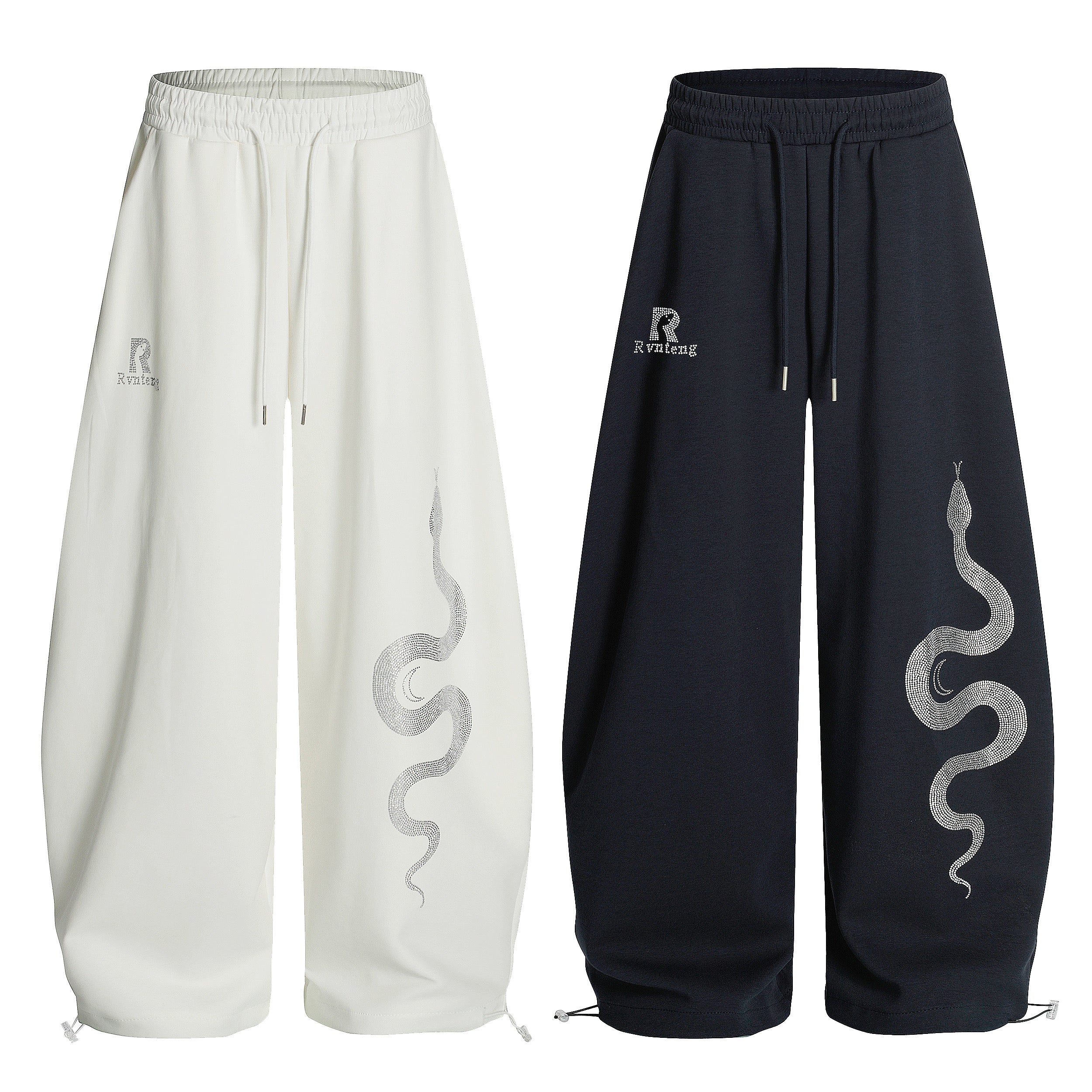 White and navy wide-leg sweatpants with silver rhinestone serpent graphic on the leg, shown side by side on white background