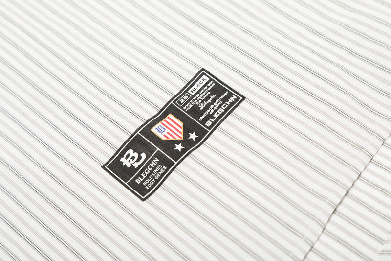 Close-up of embroidered black patch on cream striped shirt hem