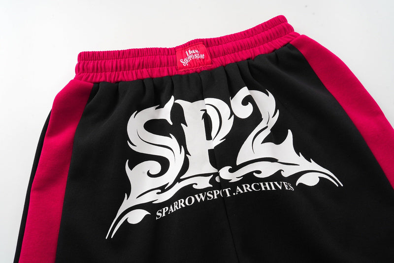 Close-up front view of SP2 logo print on black shorts with magenta side panels