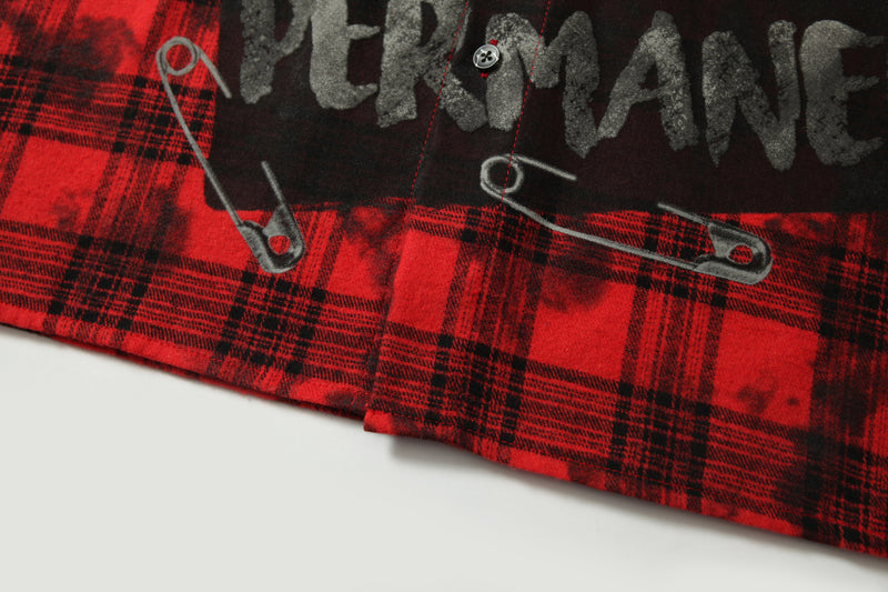 Lower front hem of red plaid shirt with safety pin graphics and cropped cut
