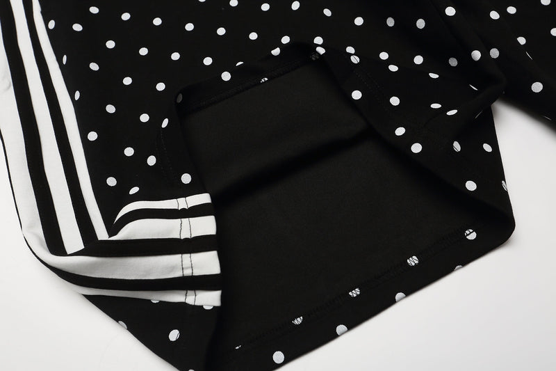 Close-up of black polka dot shorts showing the side stripe panel and rear pocket