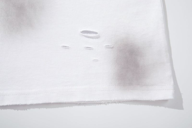 White oversized T-shirt hem with distressed cutout details and raw frayed edge on soft cotton fabric