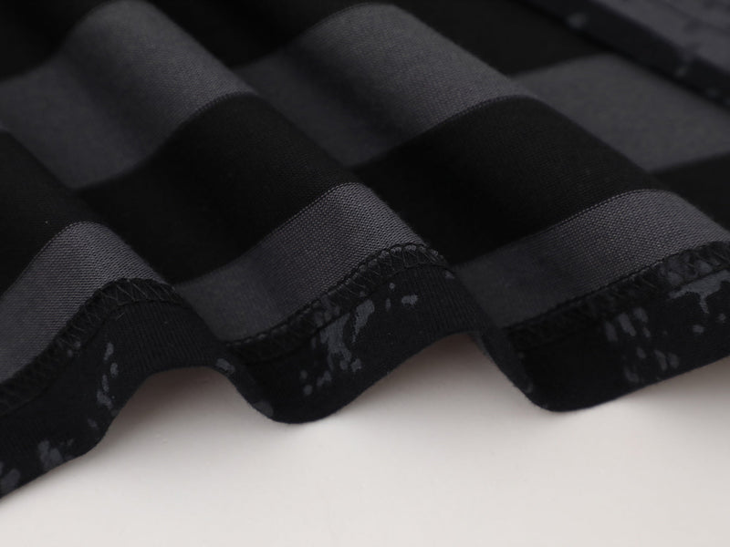 Close-up of black tee hem with ribbed striped fabric and overlocked stitching