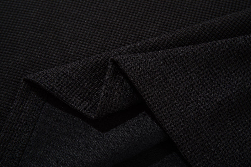 Close-up of black textured ringer T-shirt fabric with a vintage distressed streetwear look