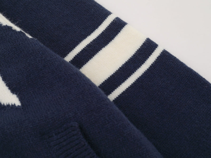 Close-up of navy sleeve with cream varsity stripes on a knit jacket