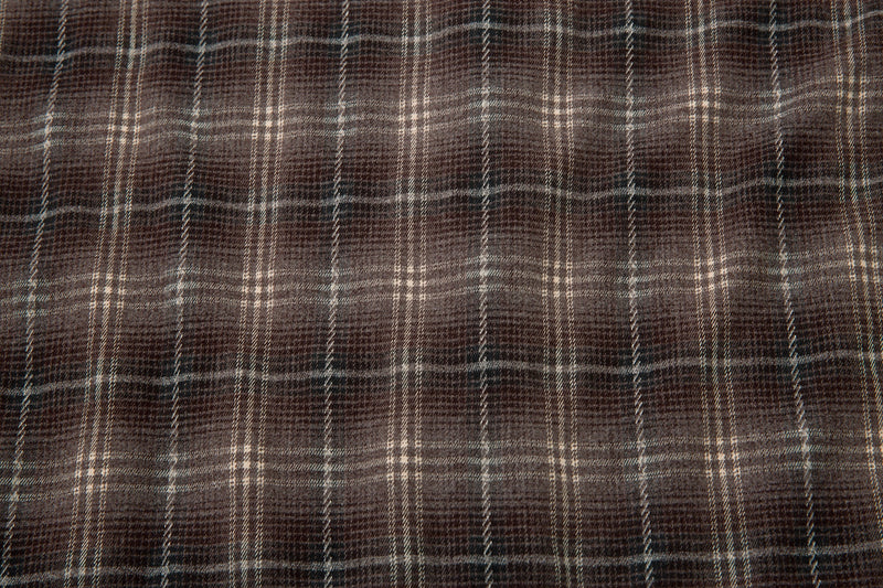 Close-up of brown plaid shirt fabric with subtle worn texture