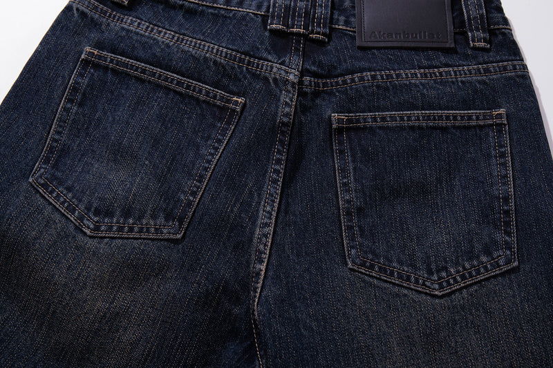Close-up of the back pockets on dark wash jeans with leather logo patch above