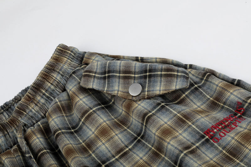 Close-up of plaid shorts snap pocket and red embroidered text on the front