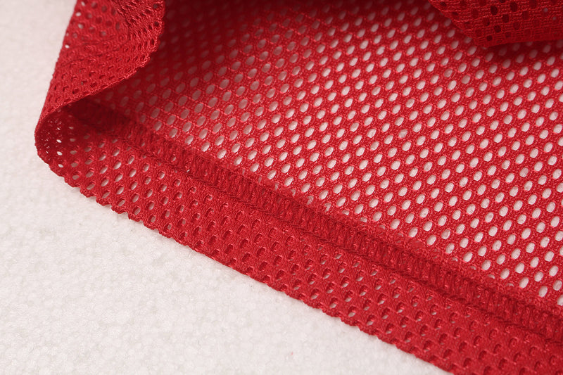 Close-up of red oversized mesh football jersey fabric with breathable perforations and stitched hem detail