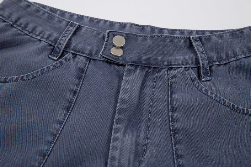 Close-up of blue denim waistband with two snap buttons and belt loops