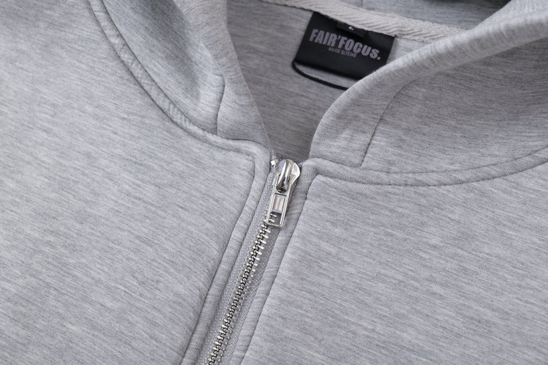 Close-up of silver front zipper and hood neckline on light gray hoodie