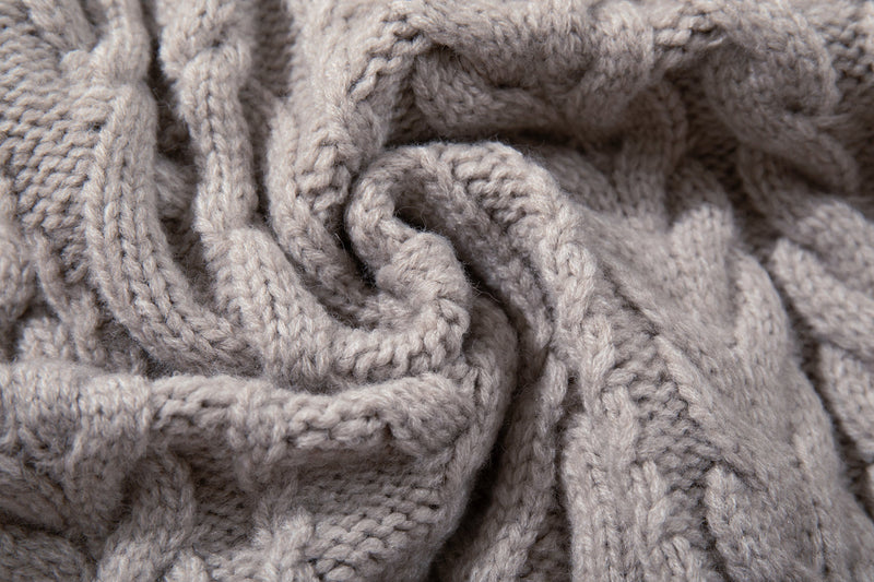 Close-up of chunky beige cable knit texture with twisted yarn detail
