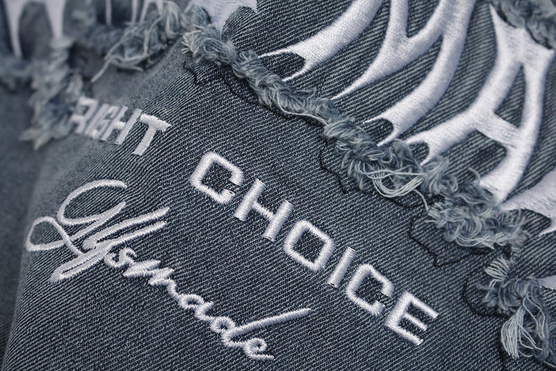 Close-up of distressed washed denim graphic tee with frayed seams and white embroidered streetwear lettering