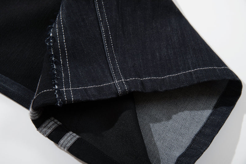 Close-up of the lower leg cuff on dark denim jeans with jersey panel insert