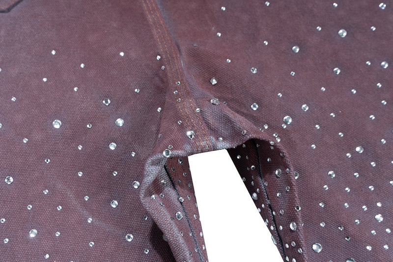 Close-up of dark brown denim crotch seam with scattered rhinestones