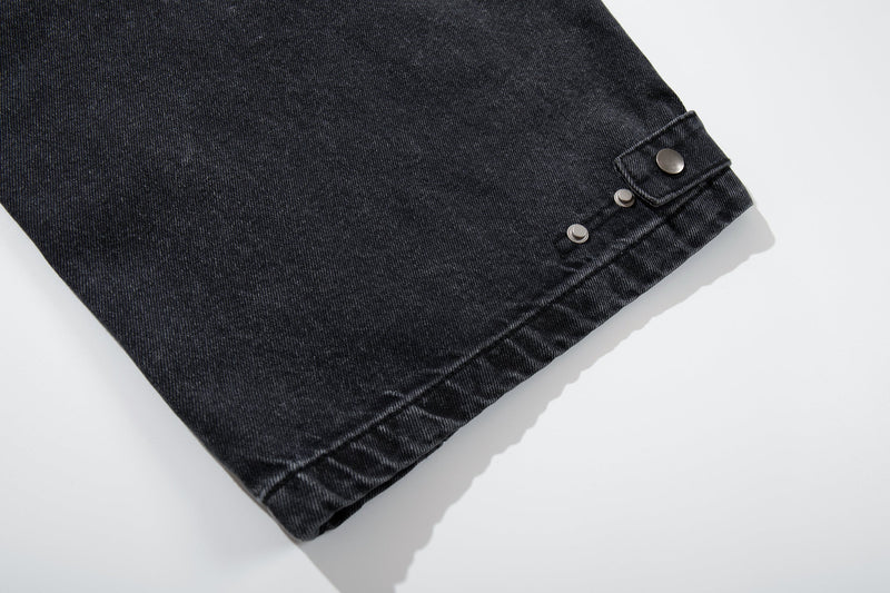 Close-up of hem strap and silver snap details on washed charcoal denim pants