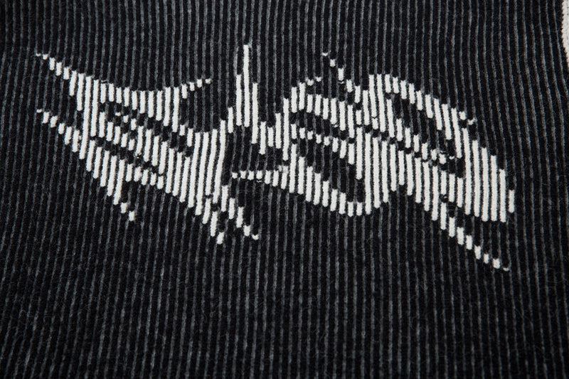 Close-up of black ribbed knit sweater with white lightning graphic details