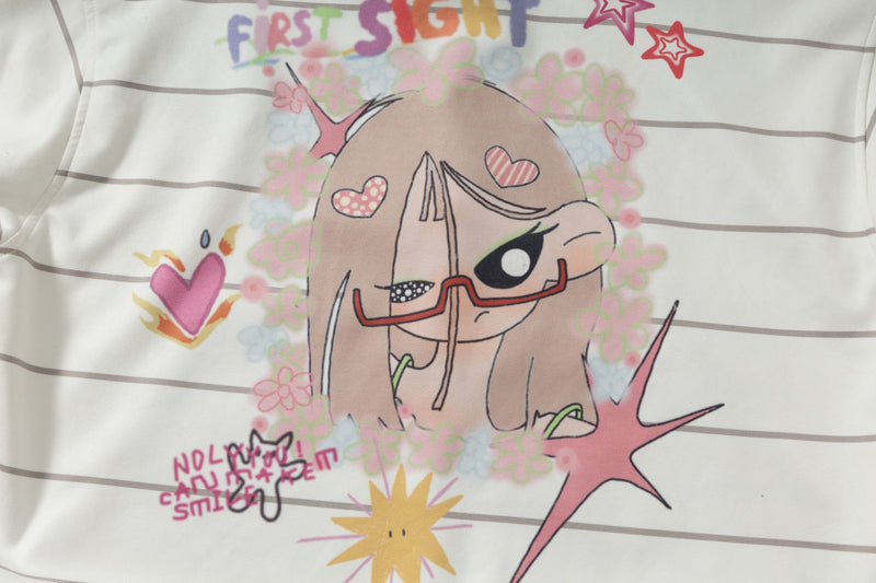 Close-up of front cartoon girl graphic with colorful text on cream striped hoodie