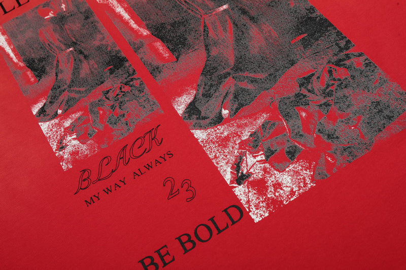 Close-up of a red vintage graphic tee with distressed black print, bold text, and streetwear-style worn texture